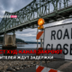 Bridge over a river with a 'ROAD CLOSED' sign and orange construction barriers; Russian headline states the Hud-Kanal Bridge will be closed and drivers face delays.
