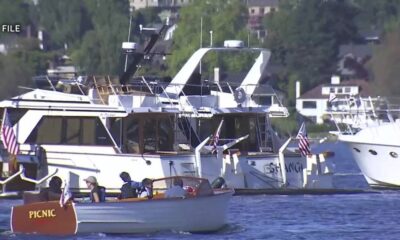 Small motorboat labeled PICNIC carrying people, cruising near larger yachts at a marina.