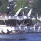 Small motorboat labeled PICNIC carrying people, cruising near larger yachts at a marina.