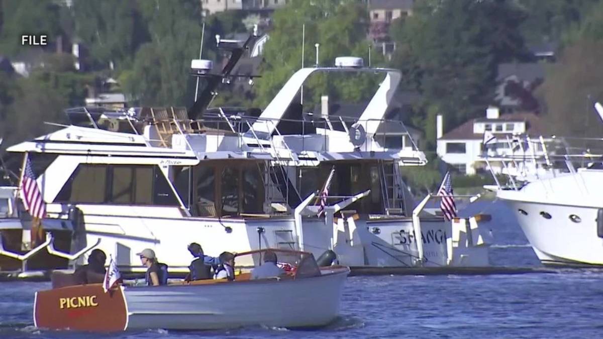 Small motorboat labeled PICNIC carrying people, cruising near larger yachts at a marina.