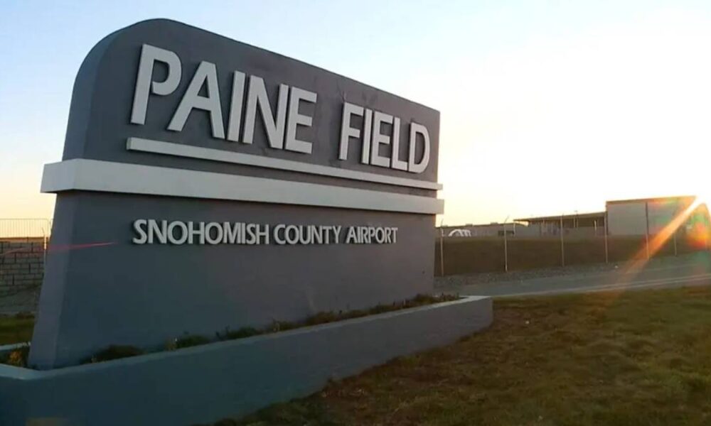 Paine Field sign at Snohomish County Airport with a sunset glare in the background.