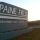Paine Field sign at Snohomish County Airport with a sunset glare in the background.