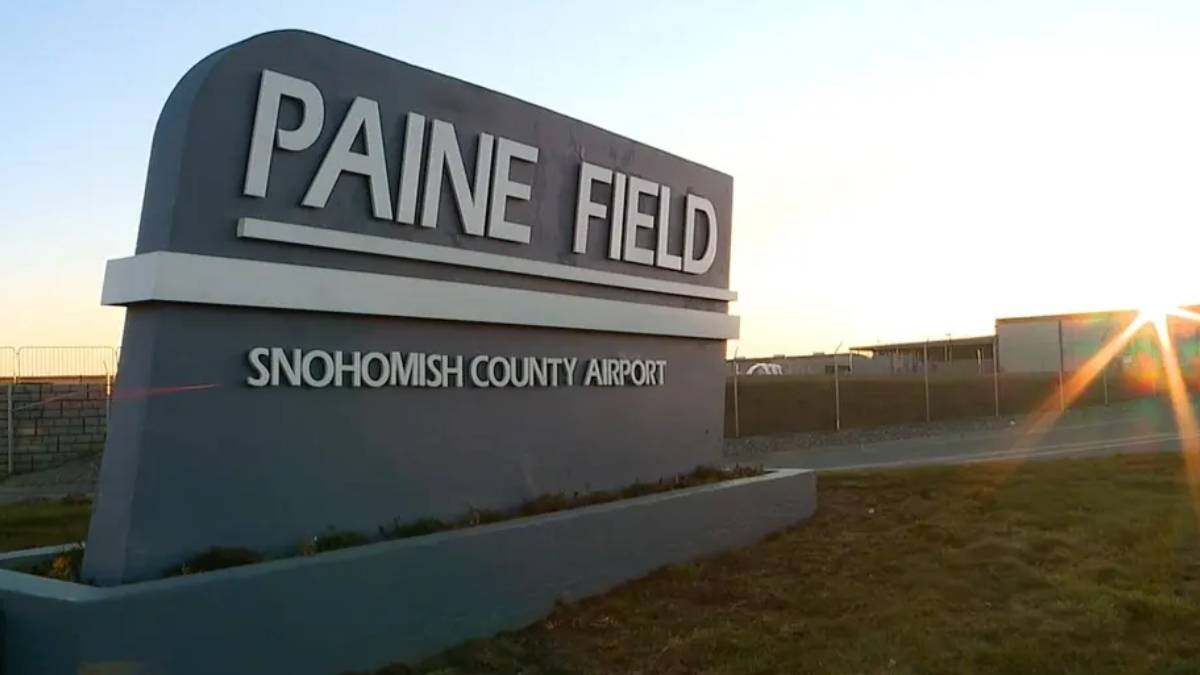 Paine Field sign at Snohomish County Airport with a sunset glare in the background.