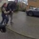 Girl grabs the arm of a man as they walk on a wet residential street; a parked car is nearby, viewed from a dashcam perspective.