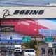 Boeing billboard towering over a busy multi-lane road with cars and green directional signs below.