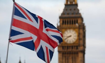 Union Jack flag fluttering in the foreground with the Big Ben clock tower in London in the background