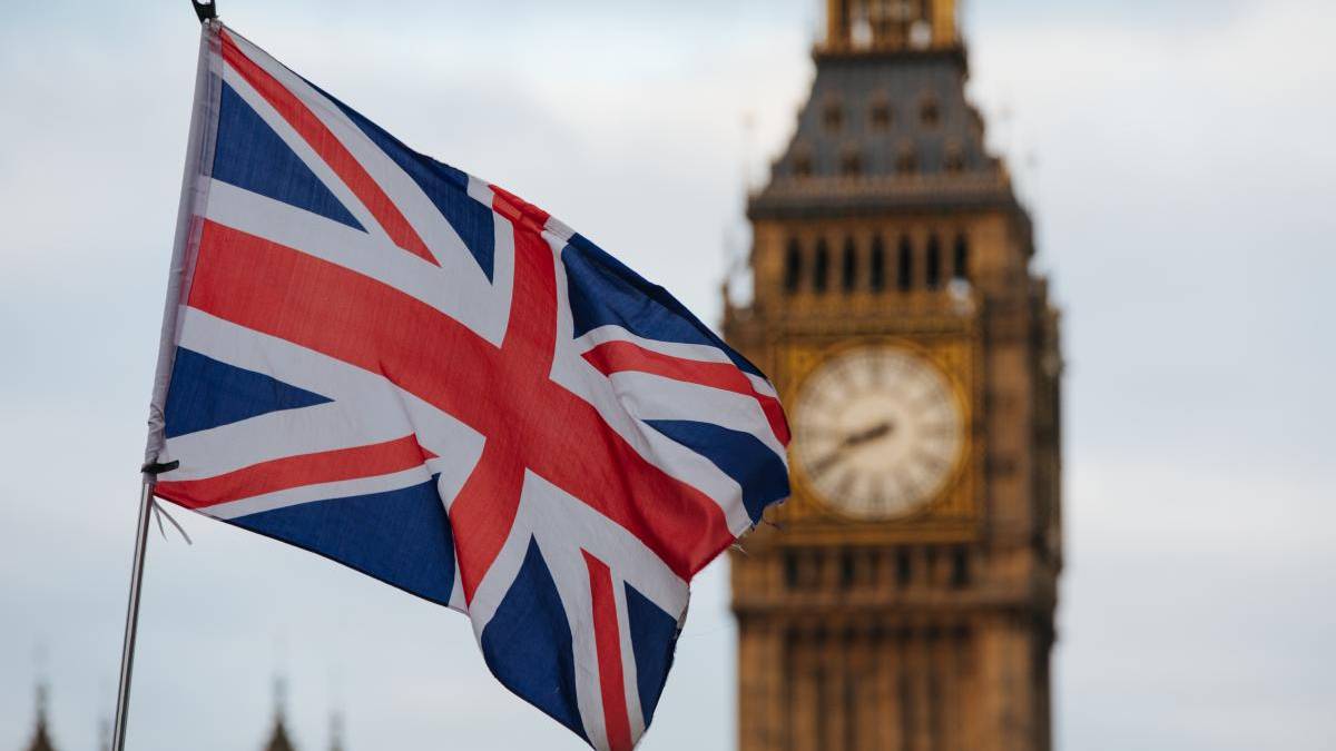 Union Jack flag fluttering in the foreground with the Big Ben clock tower in London in the background