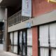 Exterior view of a pedestrian street with storefronts, featuring a blue ghost logo sign for a cafe.