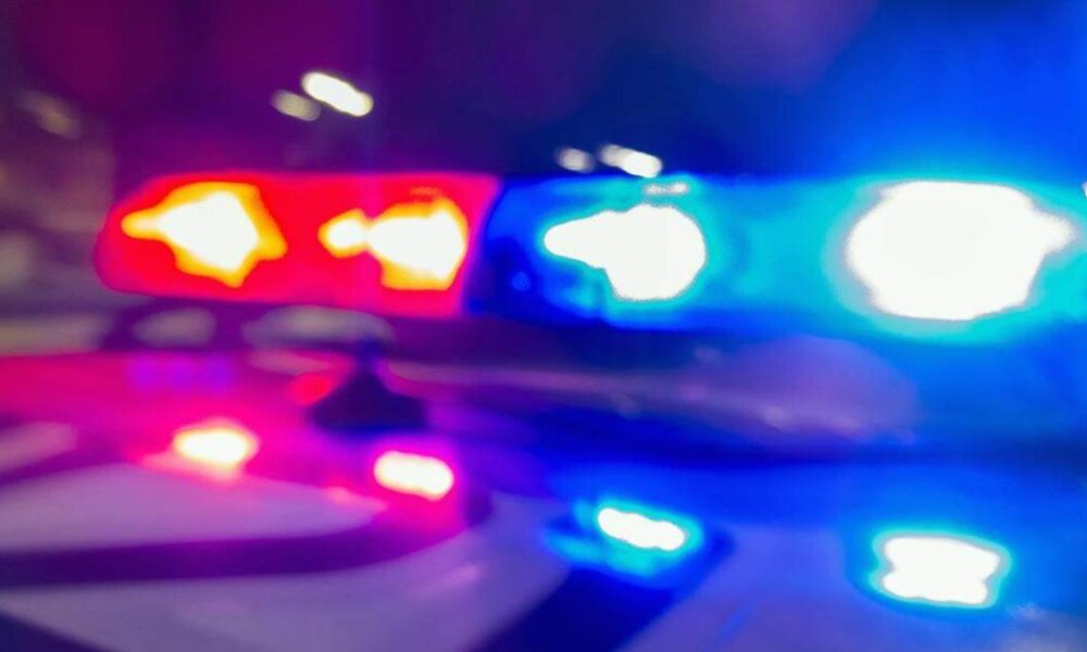 Blurred red and blue police lights flashing at night, suggesting an emergency response