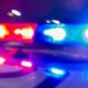 Blurred red and blue police lights flashing at night, suggesting an emergency response