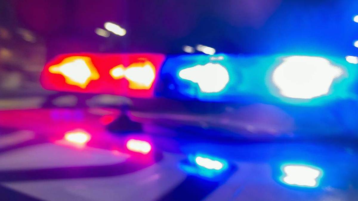 Blurred red and blue police lights flashing at night, suggesting an emergency response
