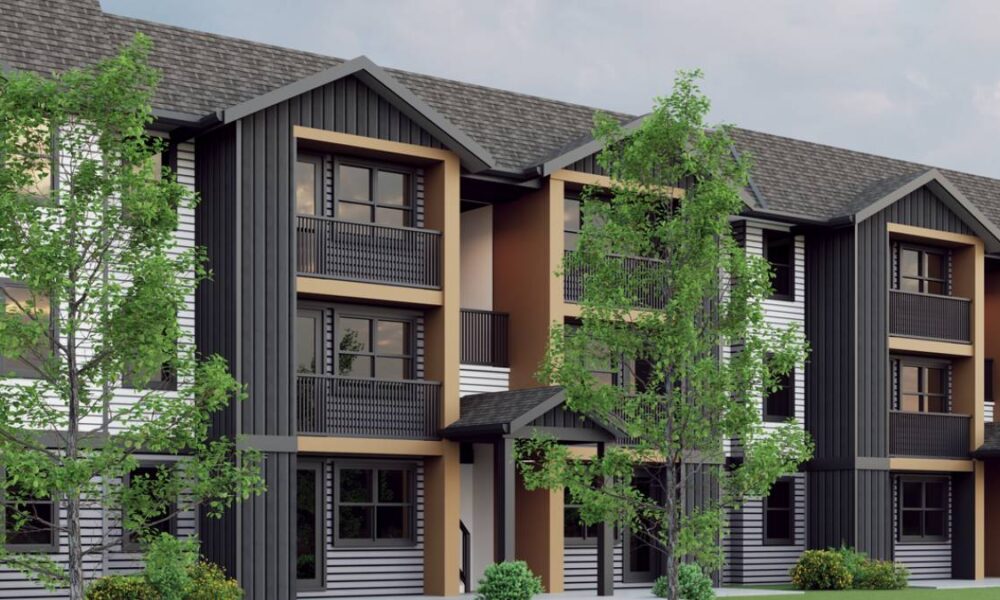 Modern townhouse building with three stories, black/gray siding, orange-brown trim, and balconies surrounded by trees.