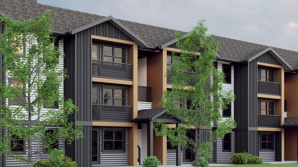 Modern townhouse building with three stories, black/gray siding, orange-brown trim, and balconies surrounded by trees.