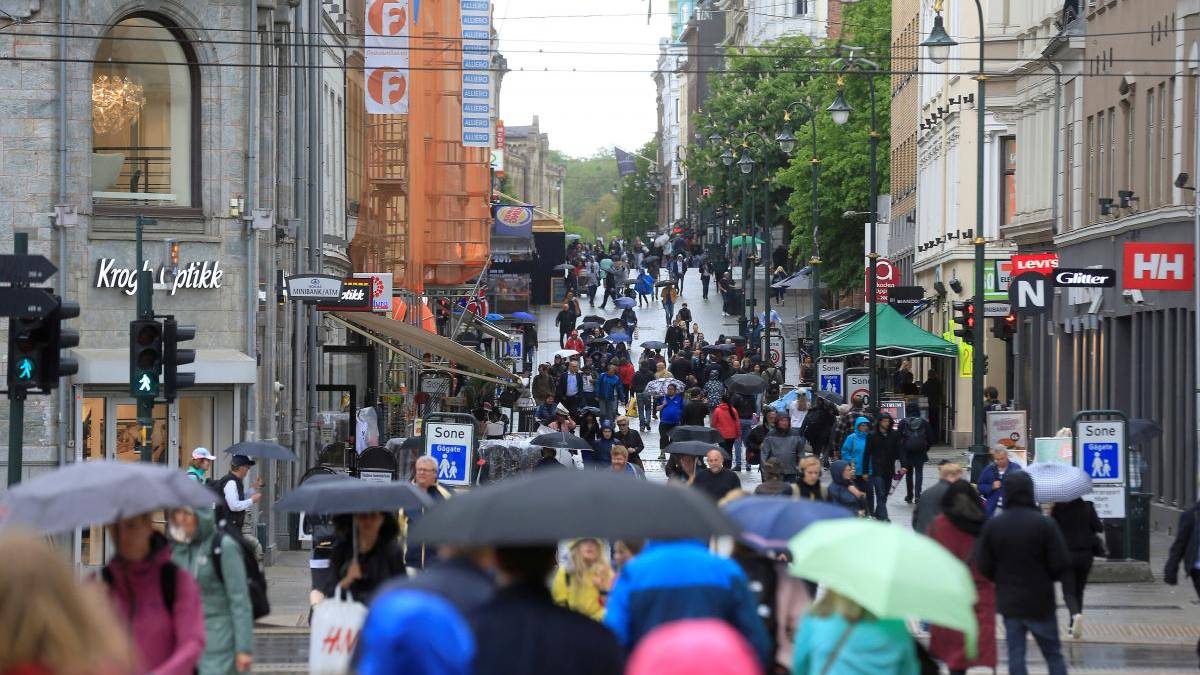 Busy city shopping street on a rainy day crowded with pedestrians and umbrellas.