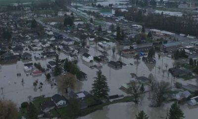 Aerial view of a town submerged in floodwater, with streets and yards filled and houses surrounded by water.