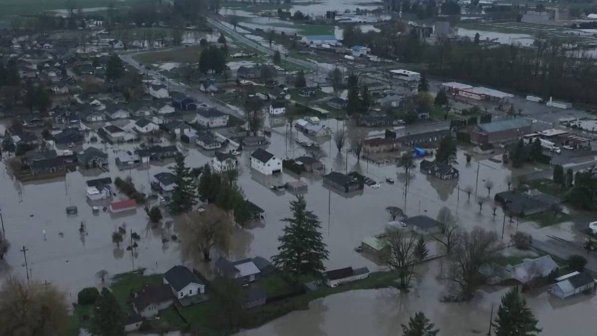 Aerial view of a town submerged in floodwater, with streets and yards filled and houses surrounded by water.