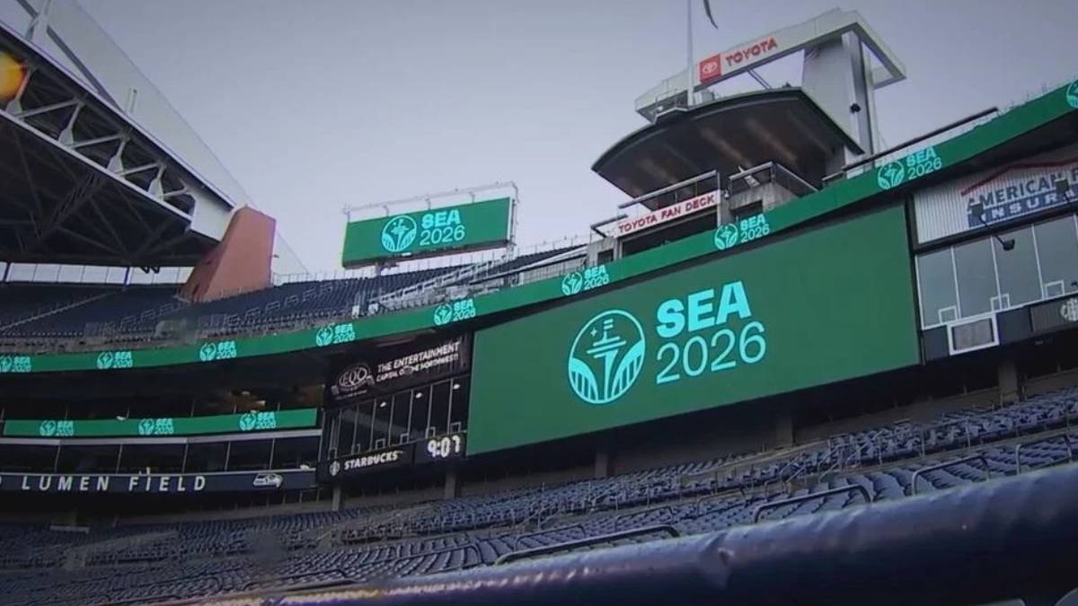 Large SEA 2026 logo on a stadium video board at Lumen Field, with empty blue seats surrounding it.