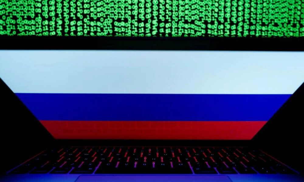 Laptop displaying the Russian flag on screen, with green binary code streaming above.