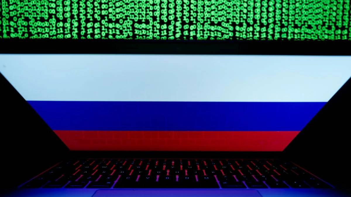 Laptop displaying the Russian flag on screen, with green binary code streaming above.