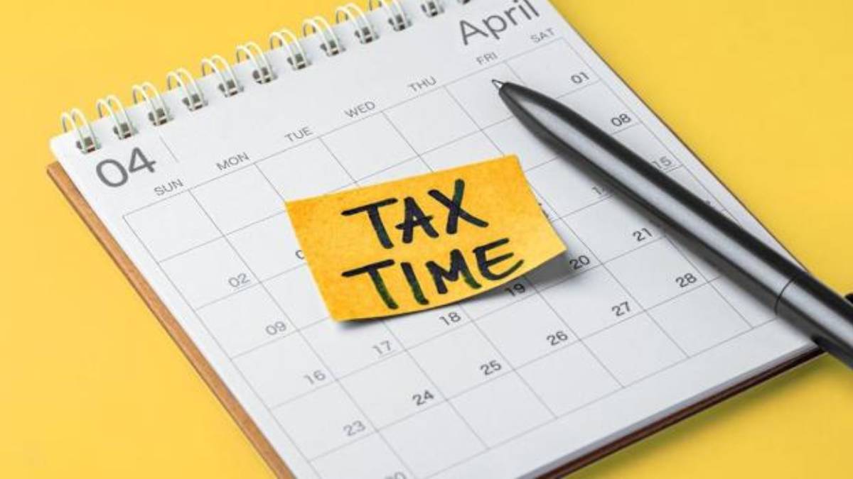 April calendar page with a yellow sticky note reading 'TAX TIME' and a pen nearby on a yellow background.