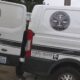 Two white vans with Seattle & King County Public Health branding and a KCME medical examiner emblem parked beside yellow caution tape.
