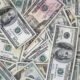 Assorted US dollar bills scattered and overlapping on a surface.