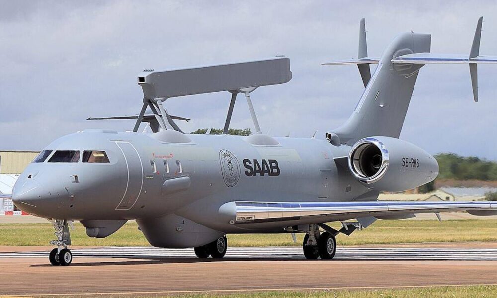 Grey Saab aircraft parked on runway with a large top-mounted radar antenna and rear-mounted engines, tail number SE-RMS visible.