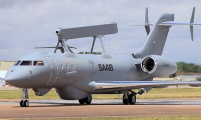 Grey Saab aircraft parked on runway with a large top-mounted radar antenna and rear-mounted engines, tail number SE-RMS visible.