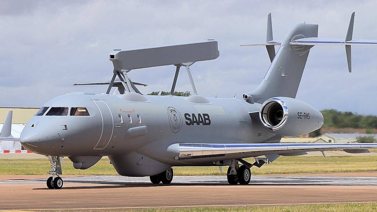 Grey Saab aircraft parked on runway with a large top-mounted radar antenna and rear-mounted engines, tail number SE-RMS visible.