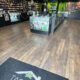Interior of a cannabis shop with glass display cases, wall shelves stocked with products, and green accents along the walls and ceiling banners.