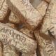 Pile of Gold Almond Roca candies in crinkled gold foil wrappers on a light surface