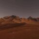 Desert plain in orange-red tones with a rocky mountain range on the horizon under a dusky sky, twilight light.