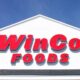WinCo Foods store sign on a white building against a blue sky