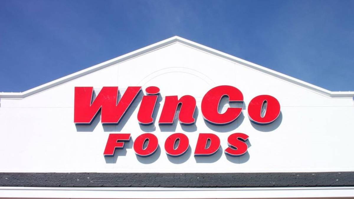 WinCo Foods store sign on a white building against a blue sky