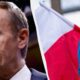 Close-up of a man in a suit speaking, with a split view showing French and Ukrainian flags on the right edge.