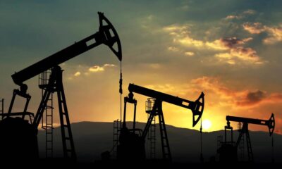 Silhouetted oil pump jacks at sunset in a desert landscape.