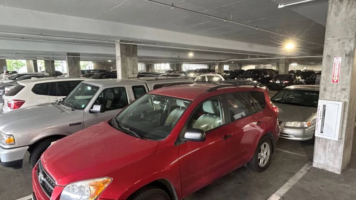 Red compact SUV in a crowded indoor parking garage with concrete pillars and many parked cars around.