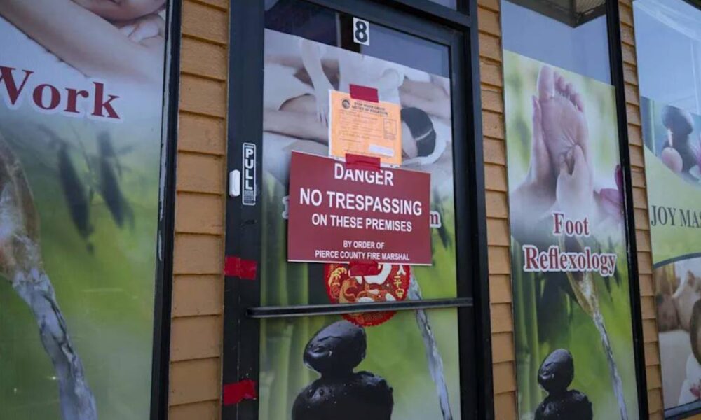 Door with red 'Danger: No Trespassing on these premises' sign; storefront windows advertise foot reflexology and massage posters in the background.