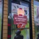 Door with red 'Danger: No Trespassing on these premises' sign; storefront windows advertise foot reflexology and massage posters in the background.