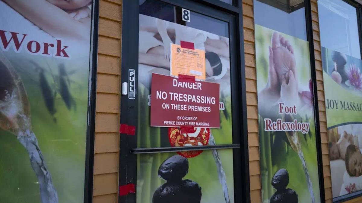 Door with red 'Danger: No Trespassing on these premises' sign; storefront windows advertise foot reflexology and massage posters in the background.