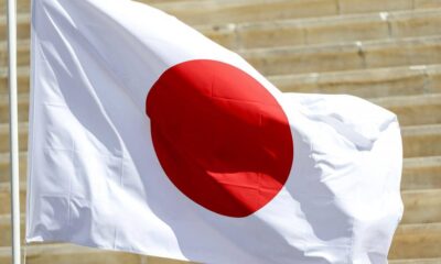 Flag of Japan waving on a pole outdoors with a red circle on white background.