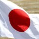 Flag of Japan waving on a pole outdoors with a red circle on white background.
