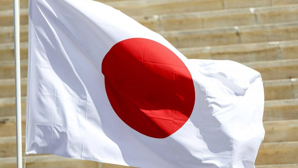 Flag of Japan waving on a pole outdoors with a red circle on white background.