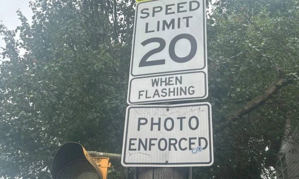 Speed limit sign reading 20 with 'When Flashing' and 'Photo Enforced' text on a street pole