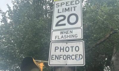 Speed limit sign reading 20 with 'When Flashing' and 'Photo Enforced' text on a street pole