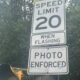 Speed limit sign reading 20 with 'When Flashing' and 'Photo Enforced' text on a street pole