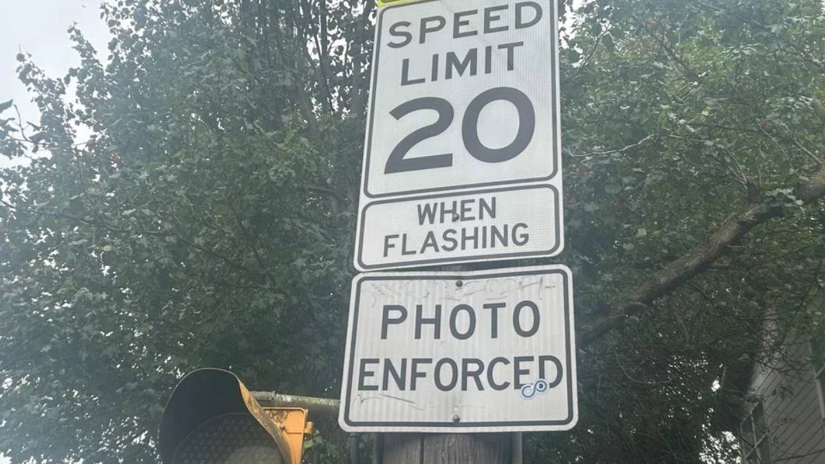 Speed limit sign reading 20 with 'When Flashing' and 'Photo Enforced' text on a street pole