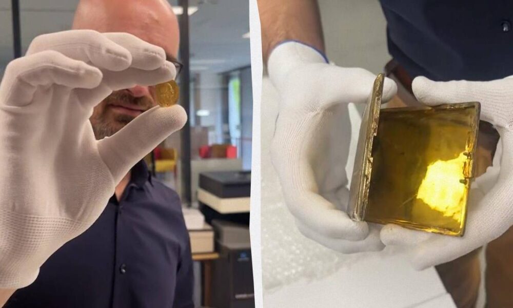 Man in gloves holding a small gold coin up to the camera in a shop or lab setting.
