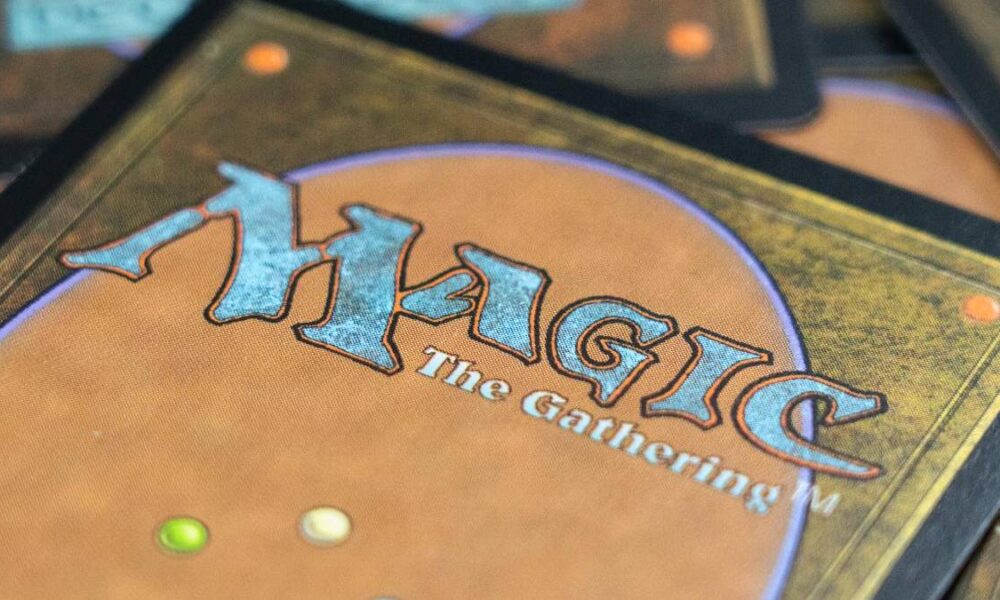 Close-up of a Magic: The Gathering card back with an orange-brown field and a blue, stylized 'MAGIC: The Gathering' logo.