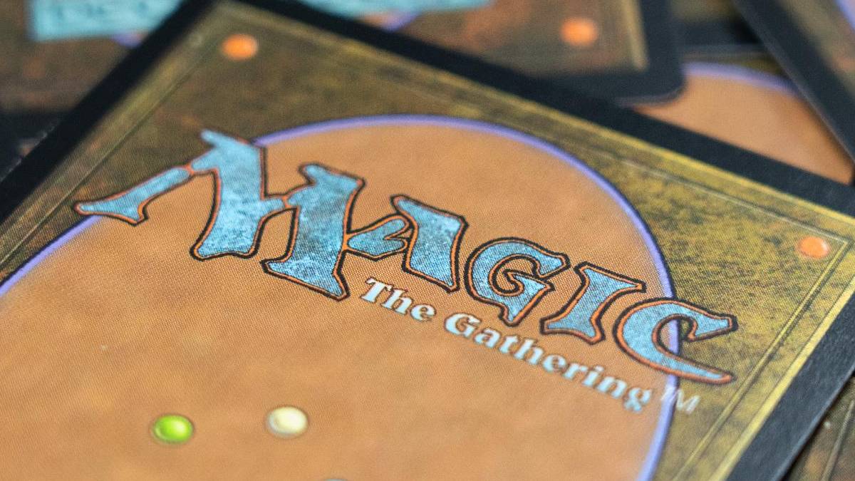 Close-up of a Magic: The Gathering card back with an orange-brown field and a blue, stylized 'MAGIC: The Gathering' logo.